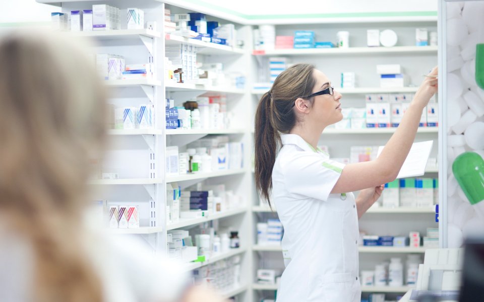 Mujer jóven técnico en farmacia acomodando lotes de medicamentos