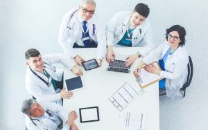 Vista de arriba de cinco médicos en reunión de trabajo - Post rentabilidad de clínicas - Blog LOLIMSA